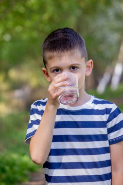Çocuk arka planda bir bardaktan su içiyor.