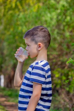 Çocuk arka planda bir bardaktan su içiyor.