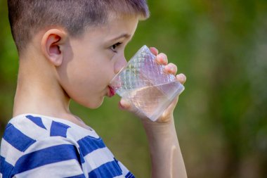 Çocuk arka planda bir bardaktan su içiyor.