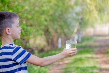 Çocuk arka planda bir bardaktan su içiyor.
