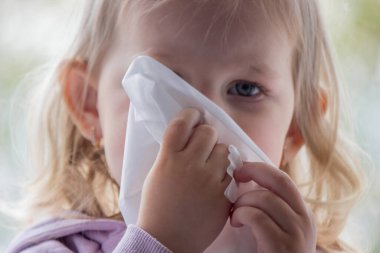 Küçük çocuk kağıt peçeteyle sümük siler, soğuk. Seçici odak.