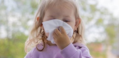 Küçük çocuk kağıt peçeteyle sümük siler, soğuk. Seçici odak.