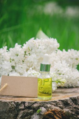 Ahşap bir kütükte leylak yağı. Kokulu yağ ve leylak çiçekli bir şişe..
