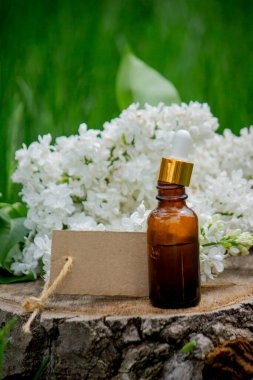 Ahşap bir kütükte leylak yağı. Kokulu yağ ve leylak çiçekli bir şişe..