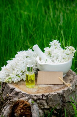 Ahşap bir kütükte leylak yağı. Kokulu yağ ve leylak çiçekli bir şişe..