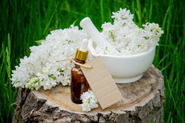 Ahşap bir kütükte leylak yağı. Kokulu yağ ve leylak çiçekli bir şişe..