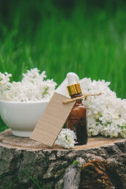 Ahşap bir kütükte leylak yağı. Kokulu yağ ve leylak çiçekli bir şişe..