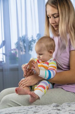 Anne yeni doğmuş bebeğin saçını özel bir saç fırçasıyla tarar. Bebek hijyeni..
