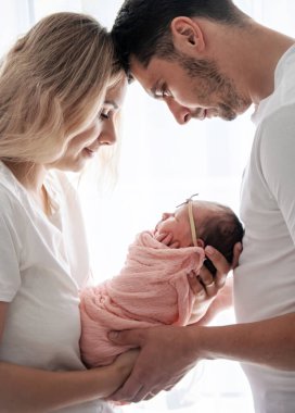 Genç bir aile, kollarında bebek tutan bir kadın ve erkek. Yeni doğan kavramı