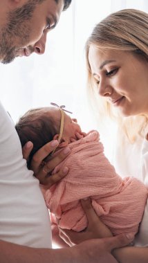 Genç bir aile, kollarında bebek tutan bir kadın ve erkek. Yeni doğan kavramı