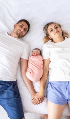 Bir adam ve bir kadın bebeklerine sarılıyor. Yeni doğan kavramı