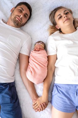 Bir adam ve bir kadın bebeklerine sarılıyor. Yeni doğan kavramı