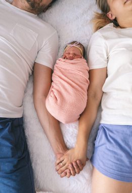 Bir adam ve bir kadın bebeklerine sarılıyor. Yeni doğan kavramı