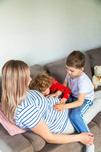 Hamile bir kadın oğlunu ve kızını kucaklıyor. Seçici odaklanma. Aşk.