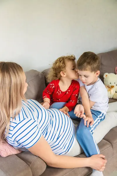 Hamile bir kadın oğlunu ve kızını kucaklıyor. Seçici odaklanma. Aşk.