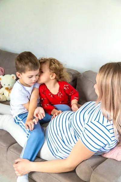 Hamile bir kadın oğlunu ve kızını kucaklıyor. Seçici odaklanma. Aşk.