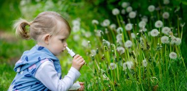 Yazın dışarıda karahindiba çiçeğine üfleyen tatlı küçük kız. Bir Çocukta Alerji