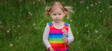 Yazın sokakta karahindiba çiçeğine üfleyen sevimli küçük kız. Çocuk Alerjisi.