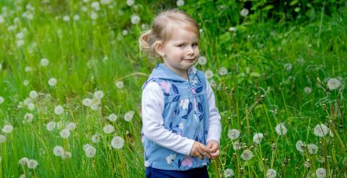 Yazın dışarıda karahindiba çiçeğine üfleyen tatlı küçük kız. Bir Çocukta Alerji