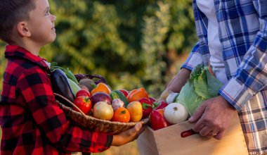 Yaşlı çiftçi kadın elinde taze sebzelerle dolu bir sandık ve elinde kase tutan bir çocuk tutuyor. Hasat et