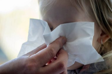 Soğuk algınlığı virüsü taşıyan küçük bir kızın yakın çekimi, sümük. Seçici odak.