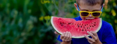 Çocuk arka planda lezzetli karpuz yiyor.