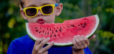 Çocuk arka planda lezzetli karpuz yiyor.