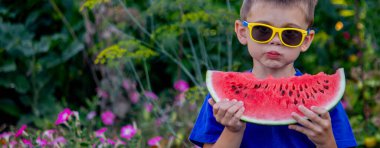 Çocuk arka planda lezzetli karpuz yiyor.