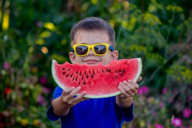 Çocuk arka planda lezzetli karpuz yiyor.