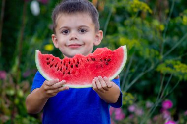 Çocuk arka planda lezzetli karpuz yiyor.