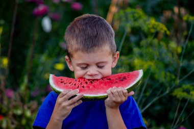 Çocuk arka planda lezzetli karpuz yiyor.