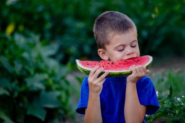 Çocuk arka planda lezzetli karpuz yiyor.