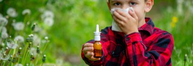 Çocuğun alerjisi var. Bir karahindiba üflüyor. Mevsimsel alerjiler. Burun akışı, sprey ve doku.