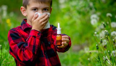 Çocuğun alerjisi var. Bir karahindiba üflüyor. Mevsimsel alerjiler. Burun akışı, sprey ve doku.
