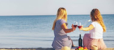 Deniz kenarında şarap içen iki kız..