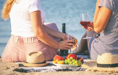 Deniz kenarında şarap içen iki kız..