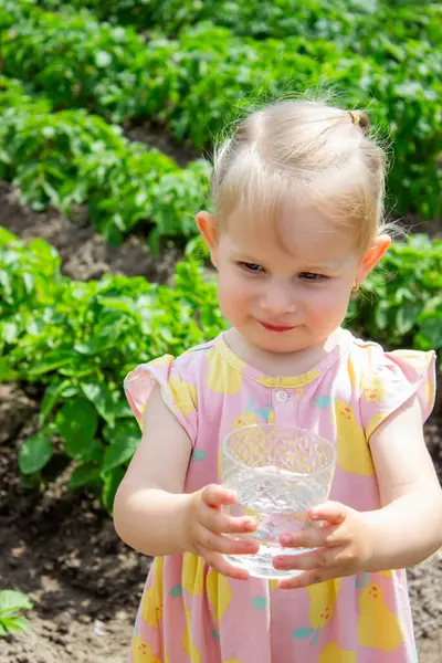 Küçük kız bahçede su içiyor. Seçici odak.