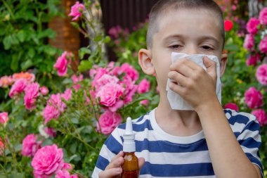 Çiçek alerjisinden hapşıran çocuk. Seçici odak.
