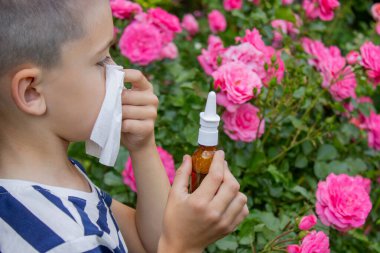 Çiçek alerjisinden hapşıran çocuk. Seçici odak.