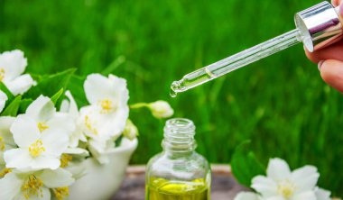 Cam şişede yasemin yağı ve yasemin çiçekleri. Yağlar