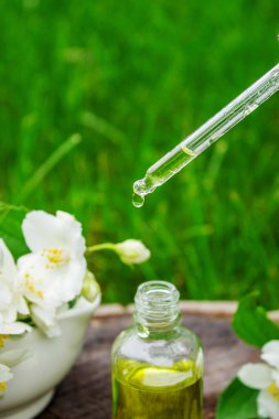 Cam şişede yasemin yağı ve yasemin çiçekleri. Yağlar