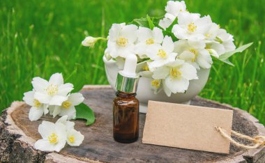 Cam şişede yasemin yağı ve yasemin çiçekleri. Yağlar
