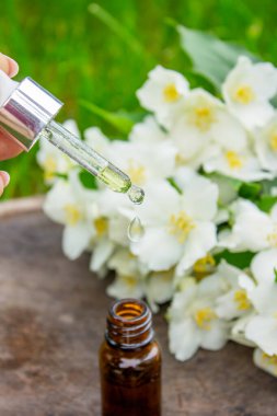 Cam şişede yasemin yağı ve yasemin çiçekleri. Yağlar