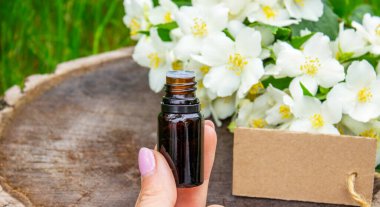 Cam şişede yasemin yağı ve yasemin çiçekleri. Yağlar