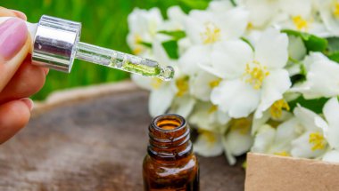 Cam şişede yasemin yağı ve yasemin çiçekleri. Yağlar