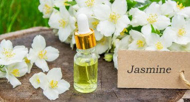 Cam şişede yasemin yağı ve yasemin çiçekleri. Yağlar