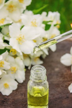 Cam şişede yasemin yağı ve yasemin çiçekleri. Yağlar