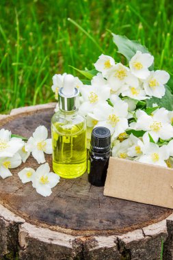 Cam şişede yasemin yağı ve yasemin çiçekleri. Yağlar