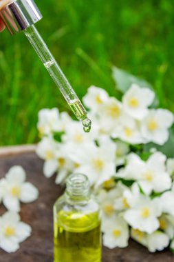 Cam şişede yasemin yağı ve yasemin çiçekleri. Yağlar