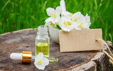 Cam şişede yasemin yağı ve yasemin çiçekleri. Yağlar